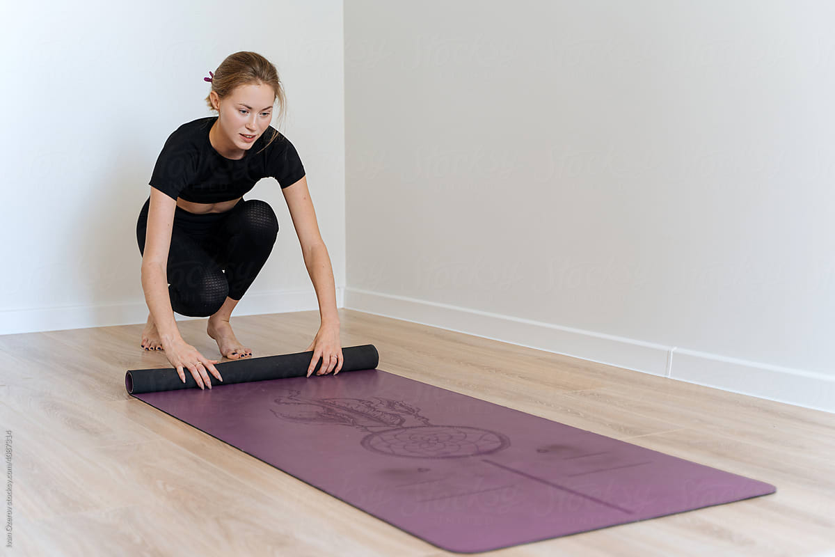 Smiling woman unrolling yoga mat