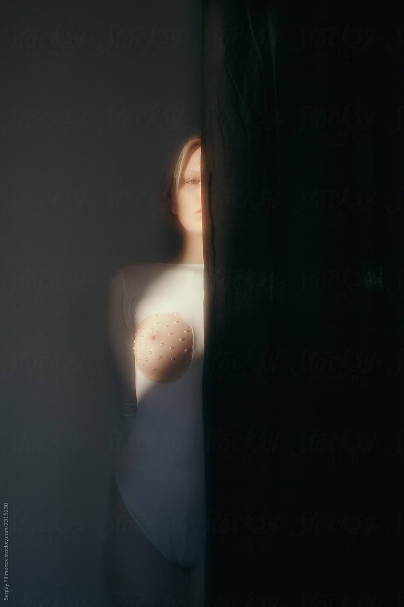 Woman with nude breast behind black curtain