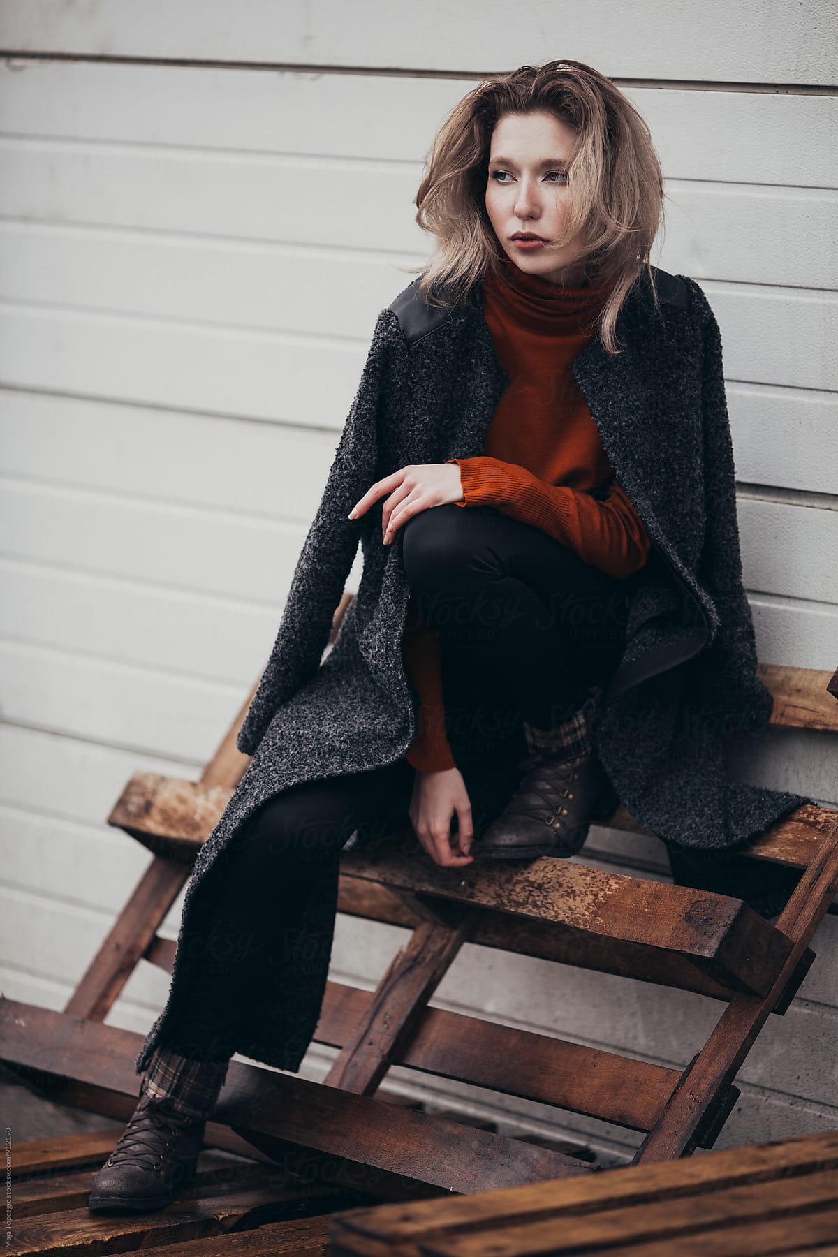 Beautiful woman in a grey coat against a white wall