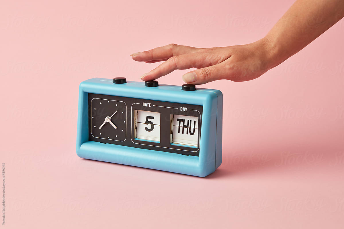 Retro style of flipping clock with calendar on a background color of the year 2019 Living Coral pantone. Girl\'s hand turns on a buttom on the clock. Place for text.