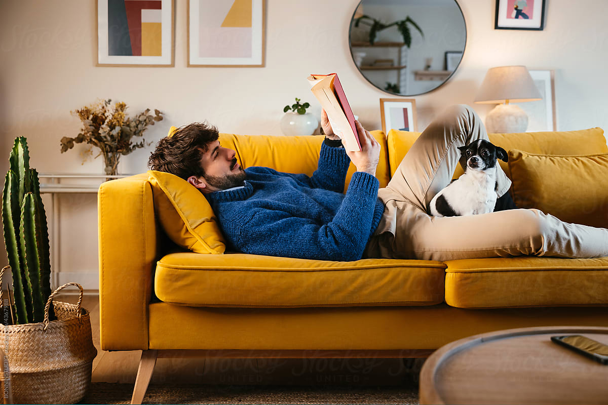 Dog owner chilling on sofa with book