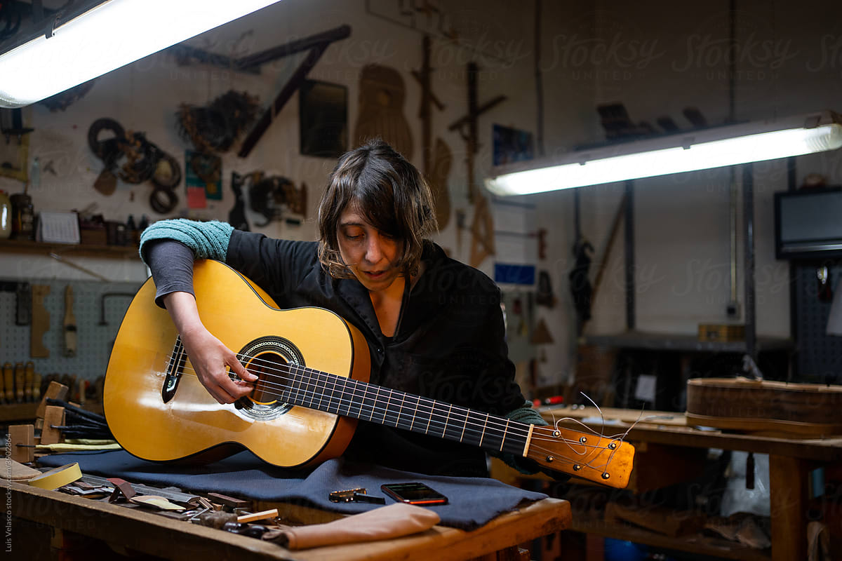 Luthier Woman Playing The Guitar In The Workshop.