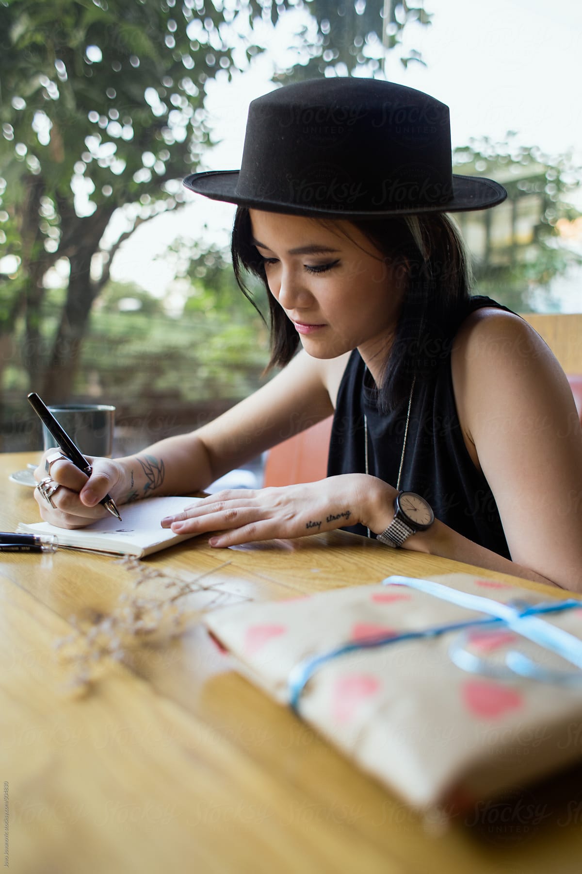 Young, stylish woman writing in her diary at a cafe