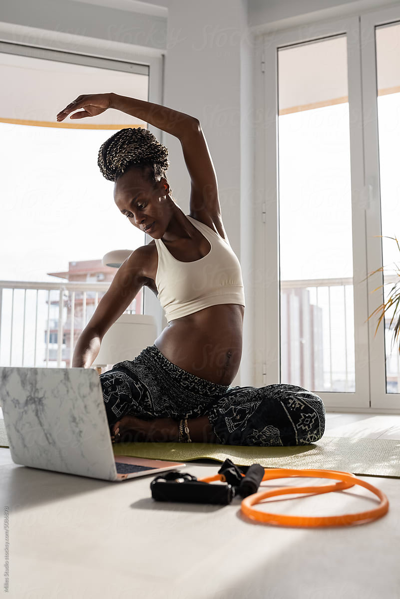 Black pregnant woman doing Seated Side Bend pose