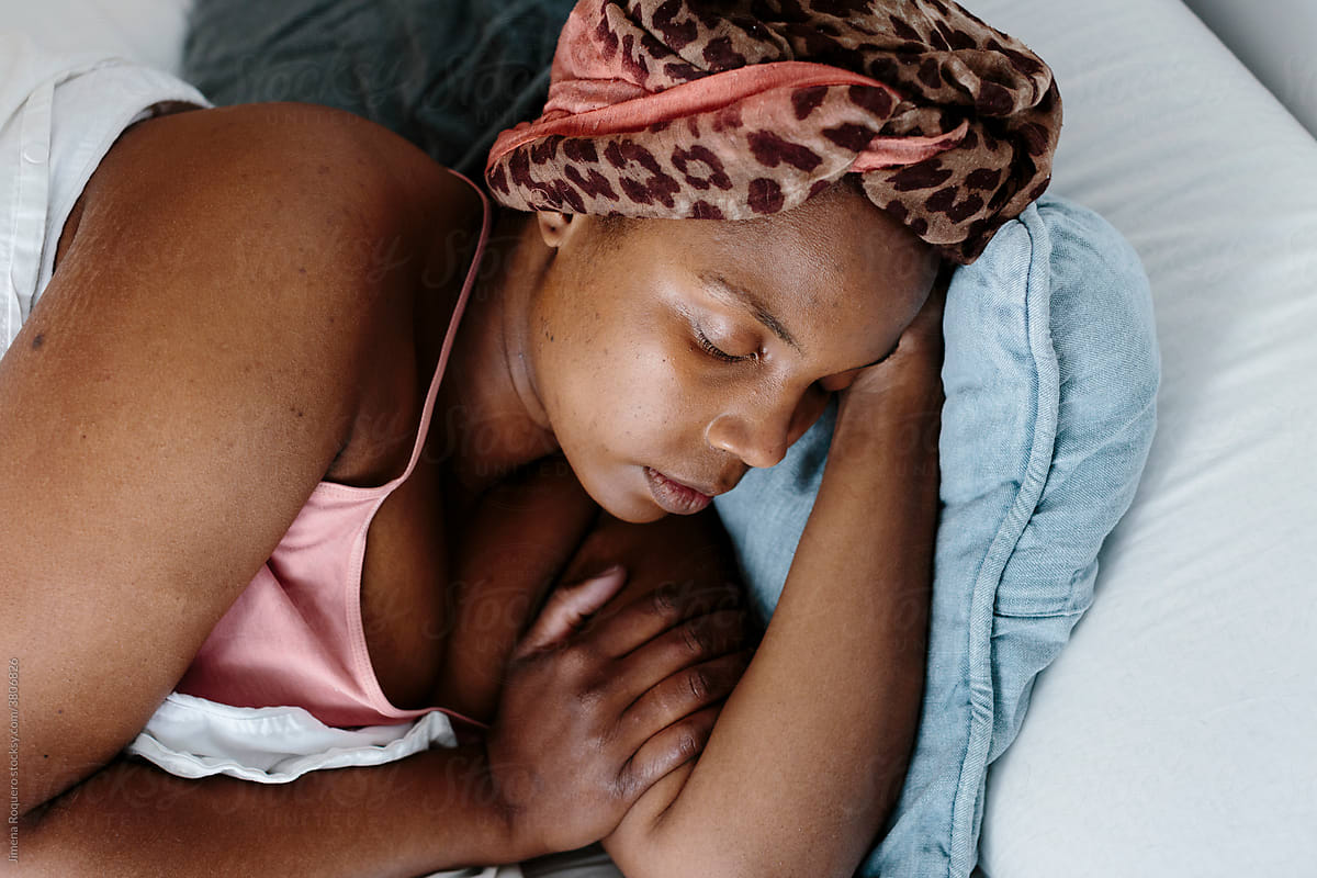 Woman with head-wrap sleeping on bed