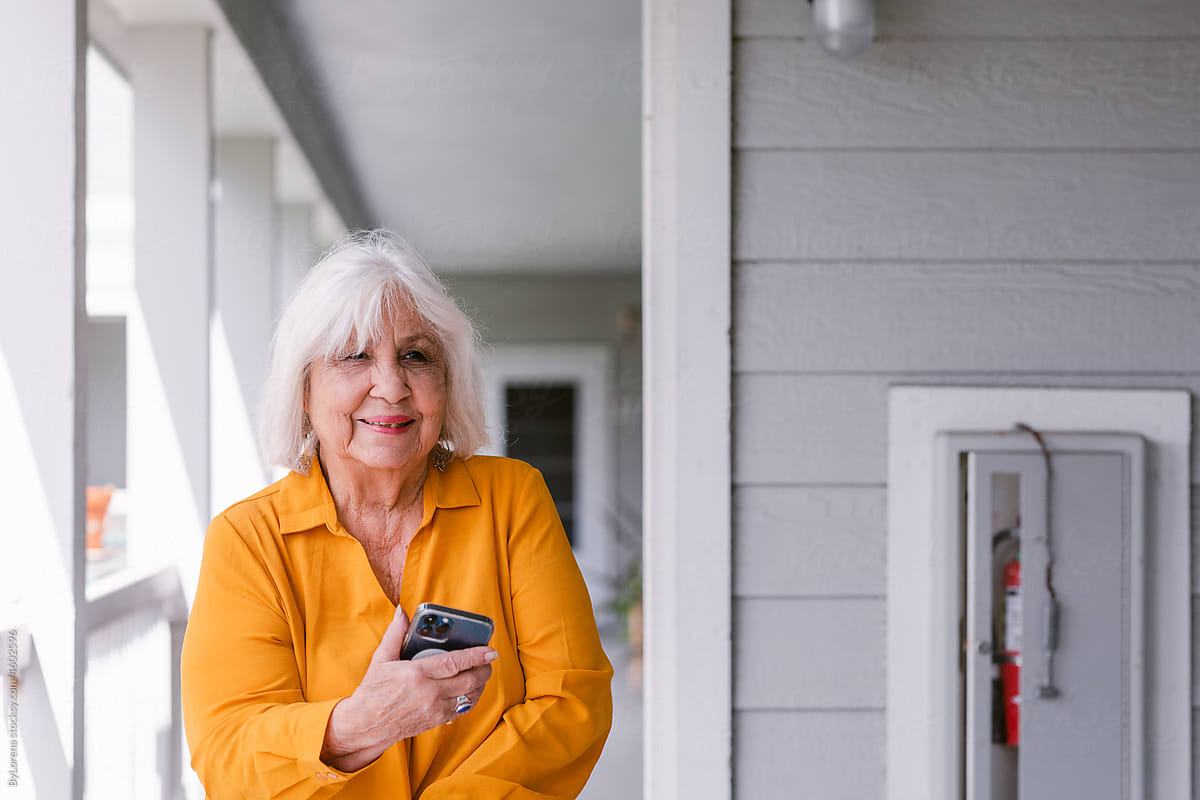 Happy Senior woman using mobile phone in open hallway outdoors