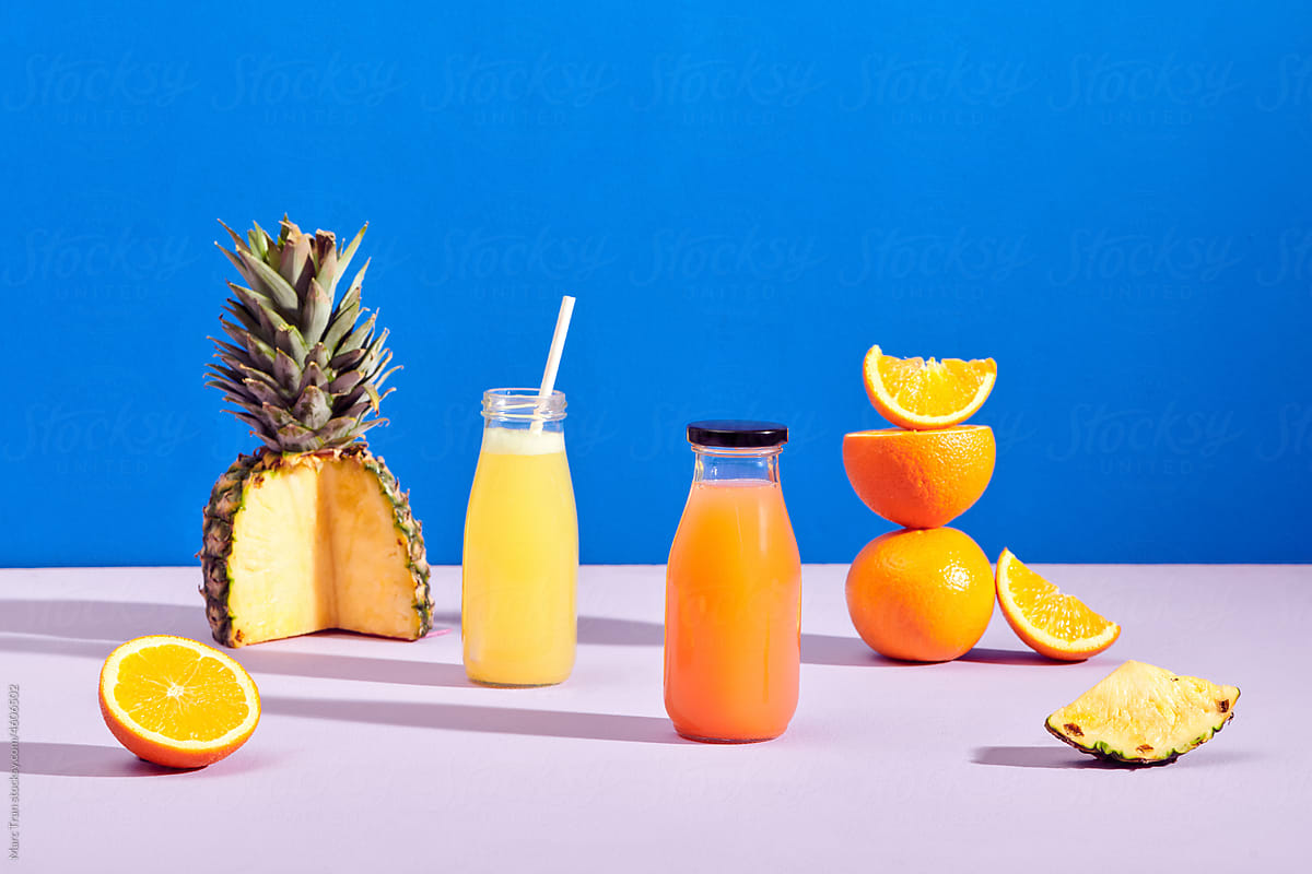 Fresh orange and pineapple juice in bottles with fresh ingredients