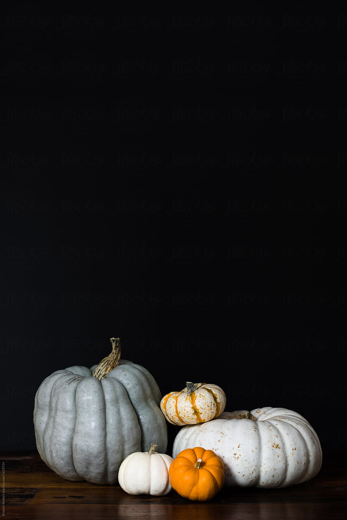 Variety of pumpkins stacked on table with dark background