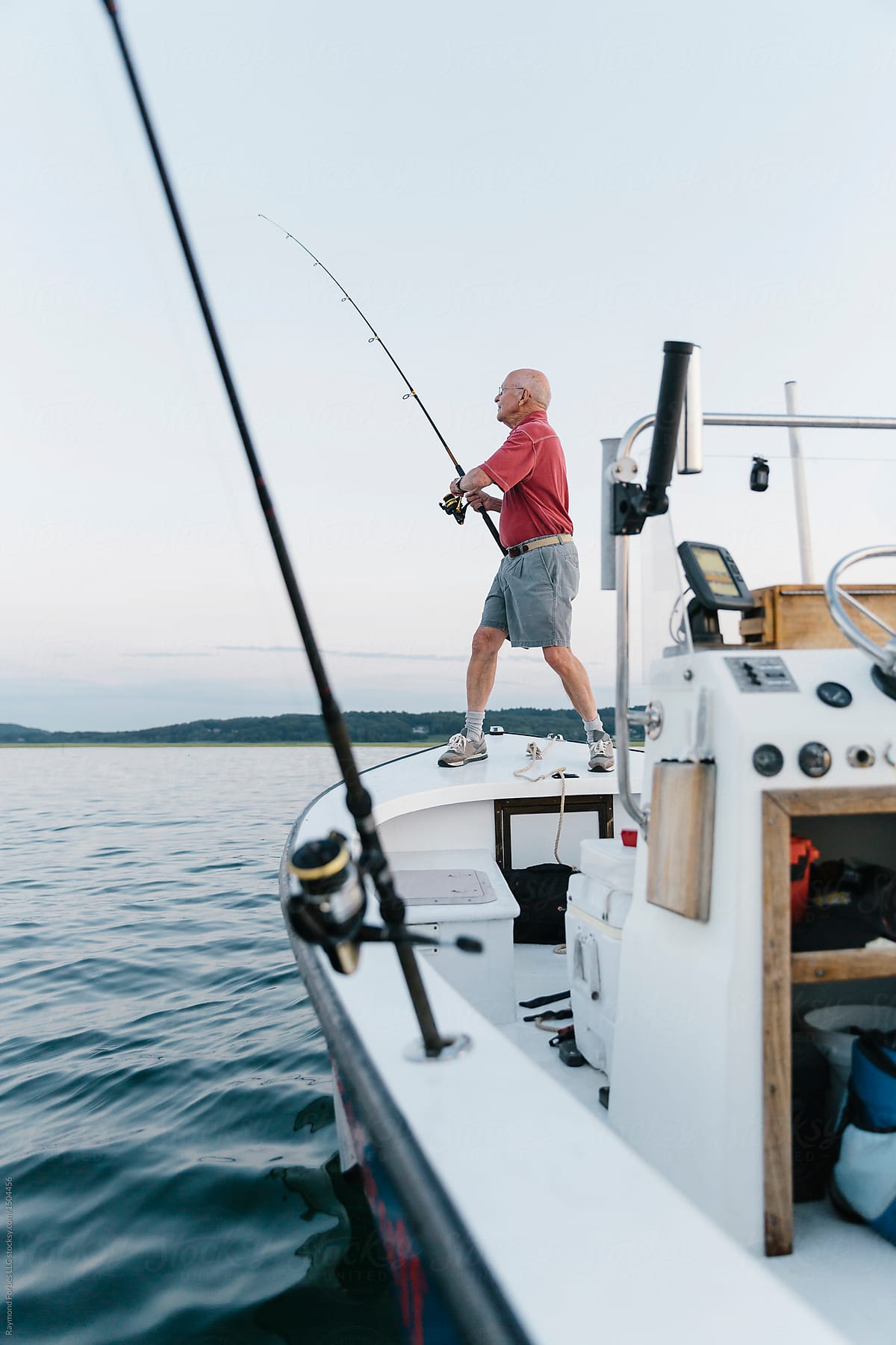 Senior Man Reeling In Fish On His Boat by Stocksy Contributor Raymond  Forbes LLC - Stocksy