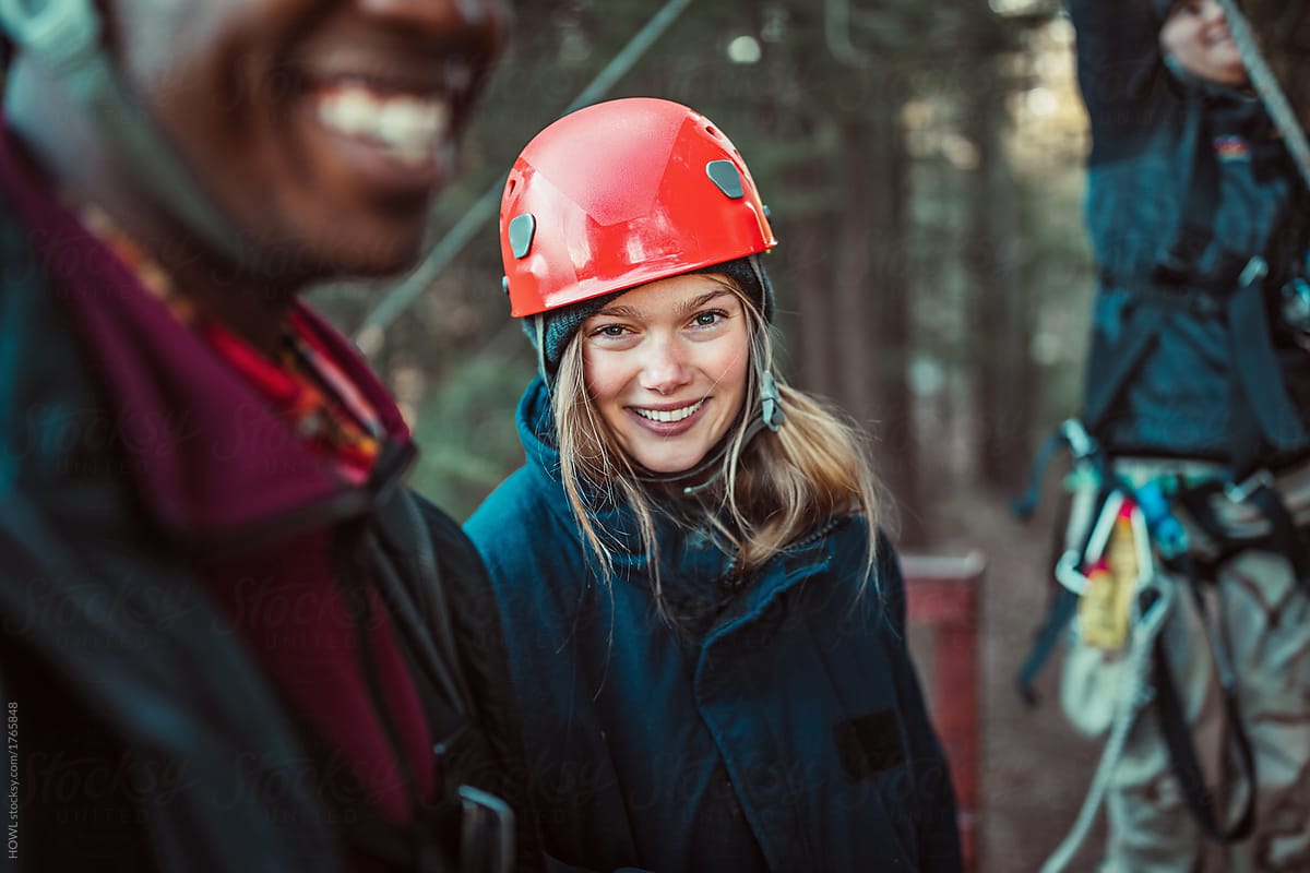 A young woman smiles with friends during an outdoor zip line course