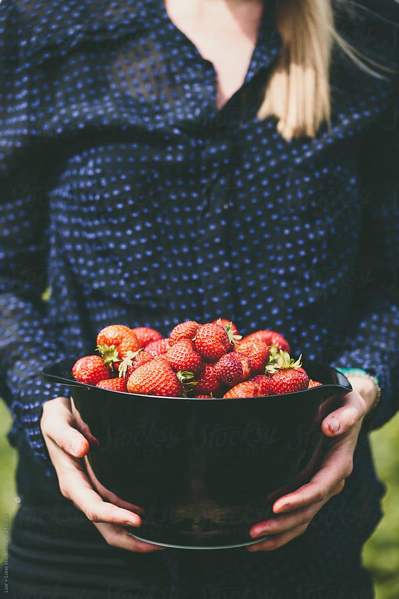 Closeup of a womanâs hands holding fresh strawberries