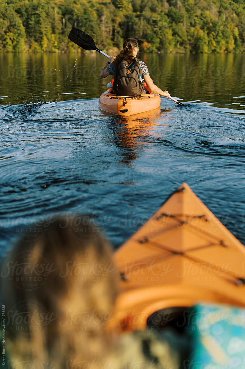 Two kayakers with children on a lake