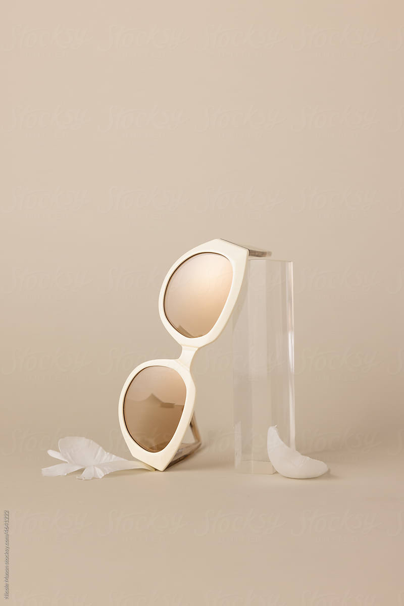 pair of sunglasses with gold lenses leaning on acrylic prop