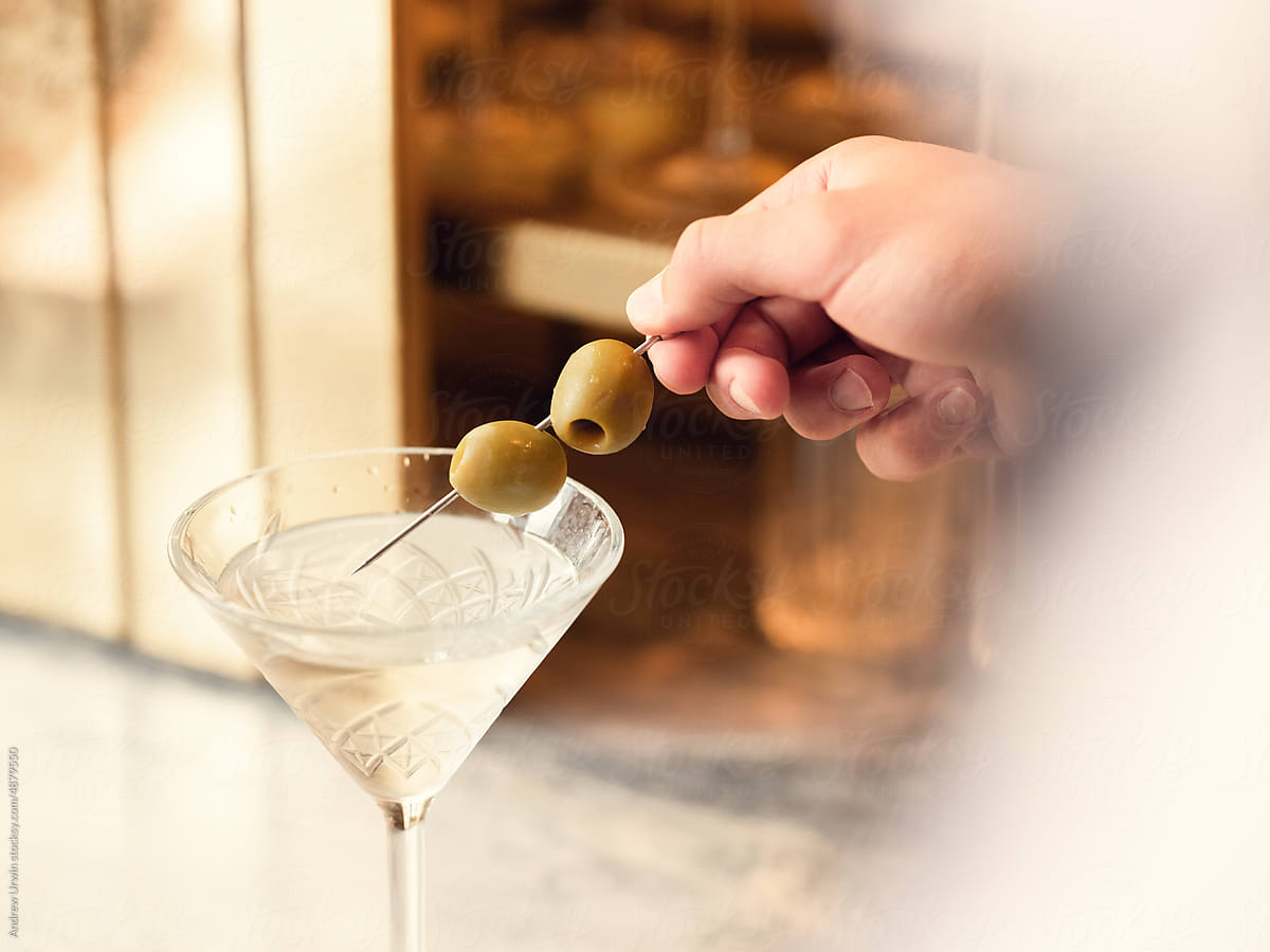 A dirty martini with olives being places on top