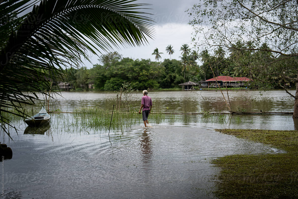 A fisherman wades through a river flooding into the jungle in Thailand