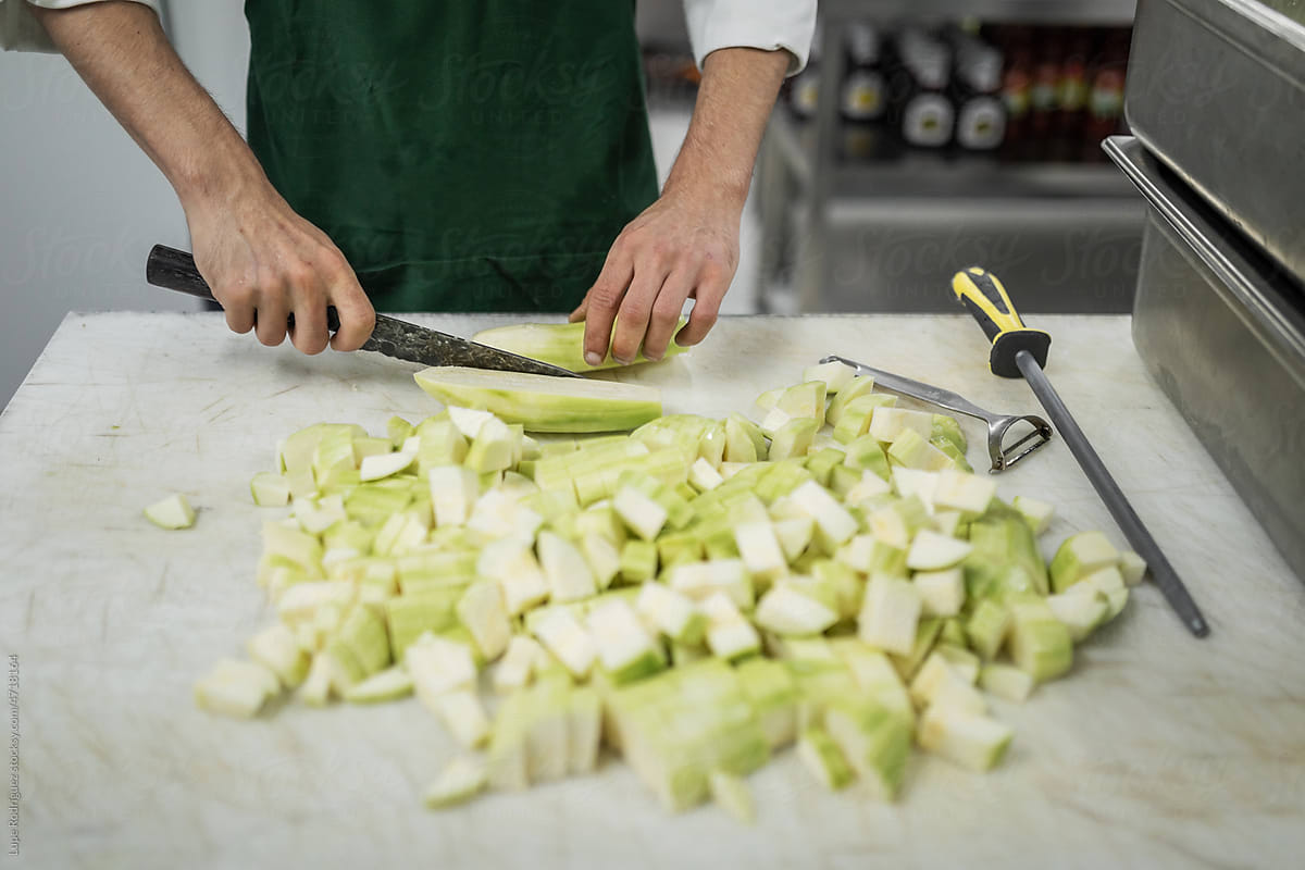 Anonymous chef cutting a courgette in a restaurant kitchen