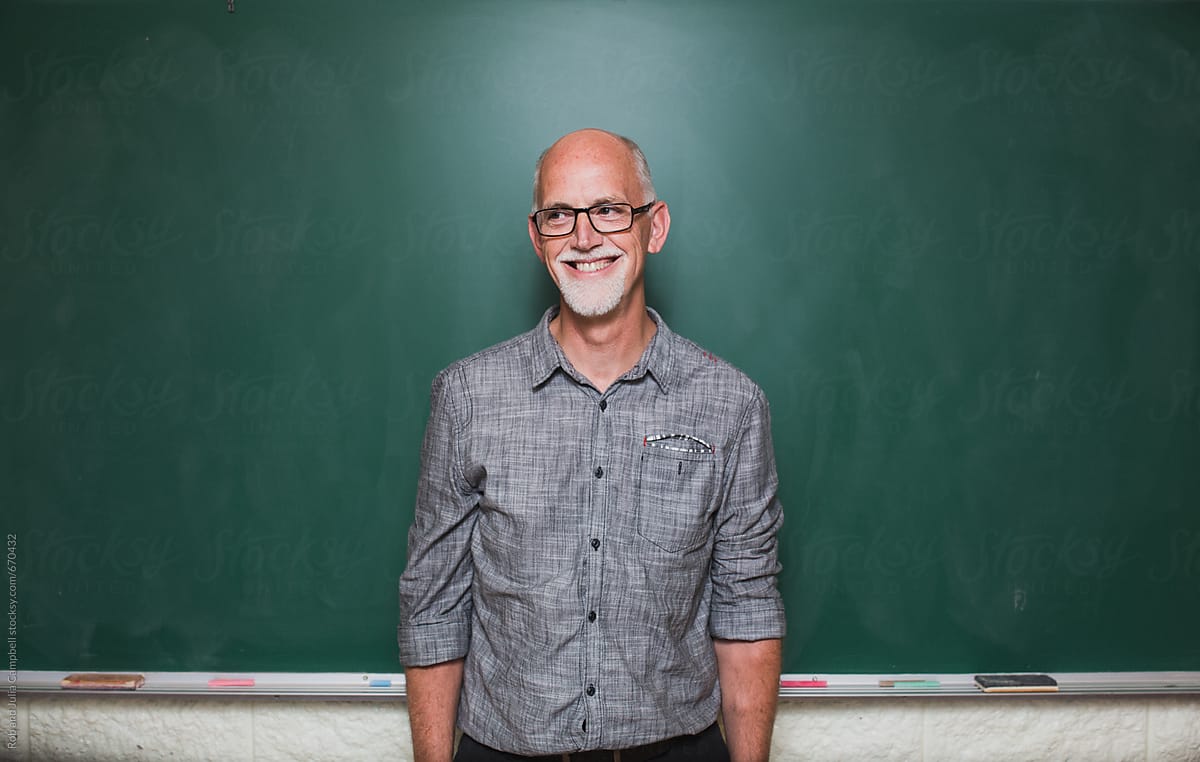 Happy smiling older gentleman standing near chalkboard