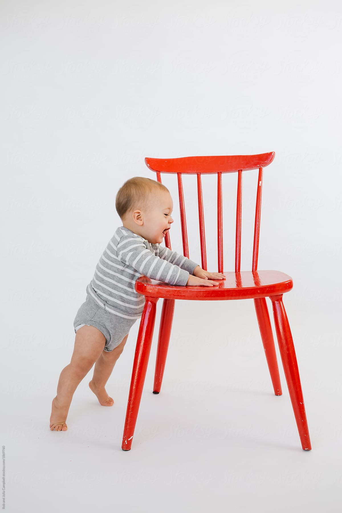 Cute baby standing up with red chair on 