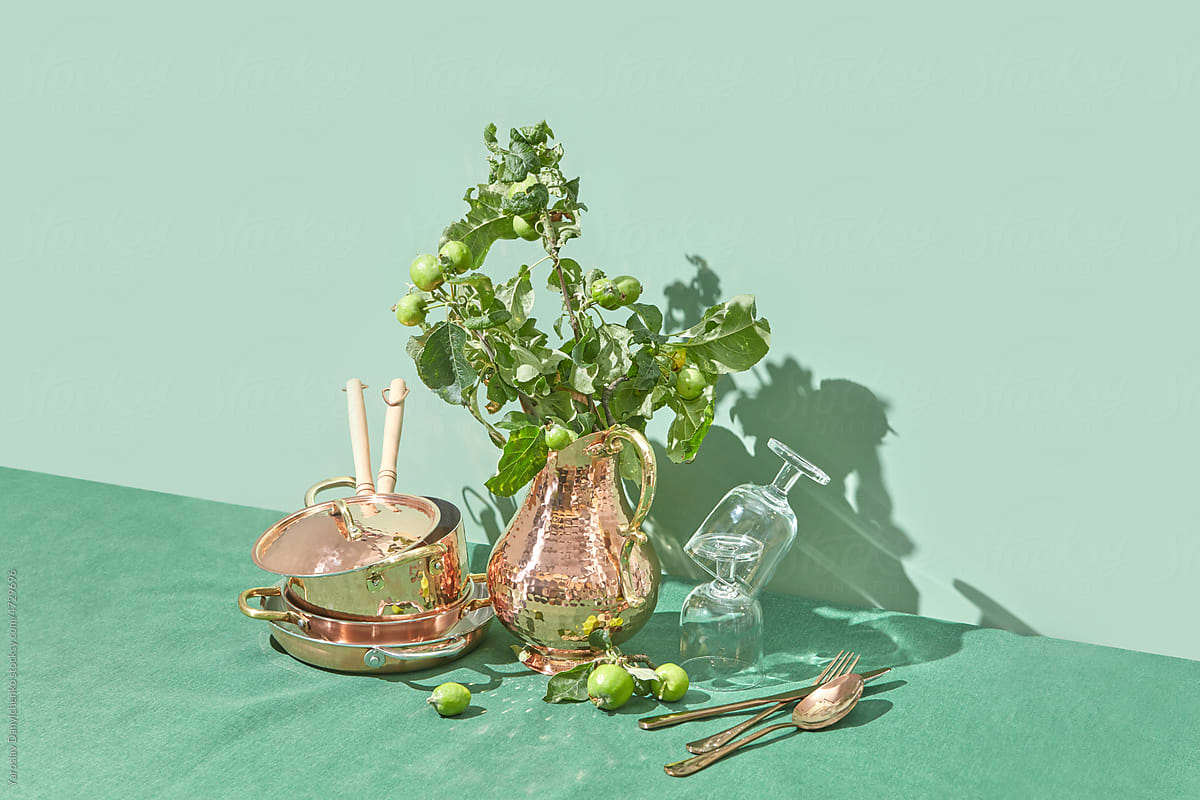 Copper kitchenware decorated with green tree branches.