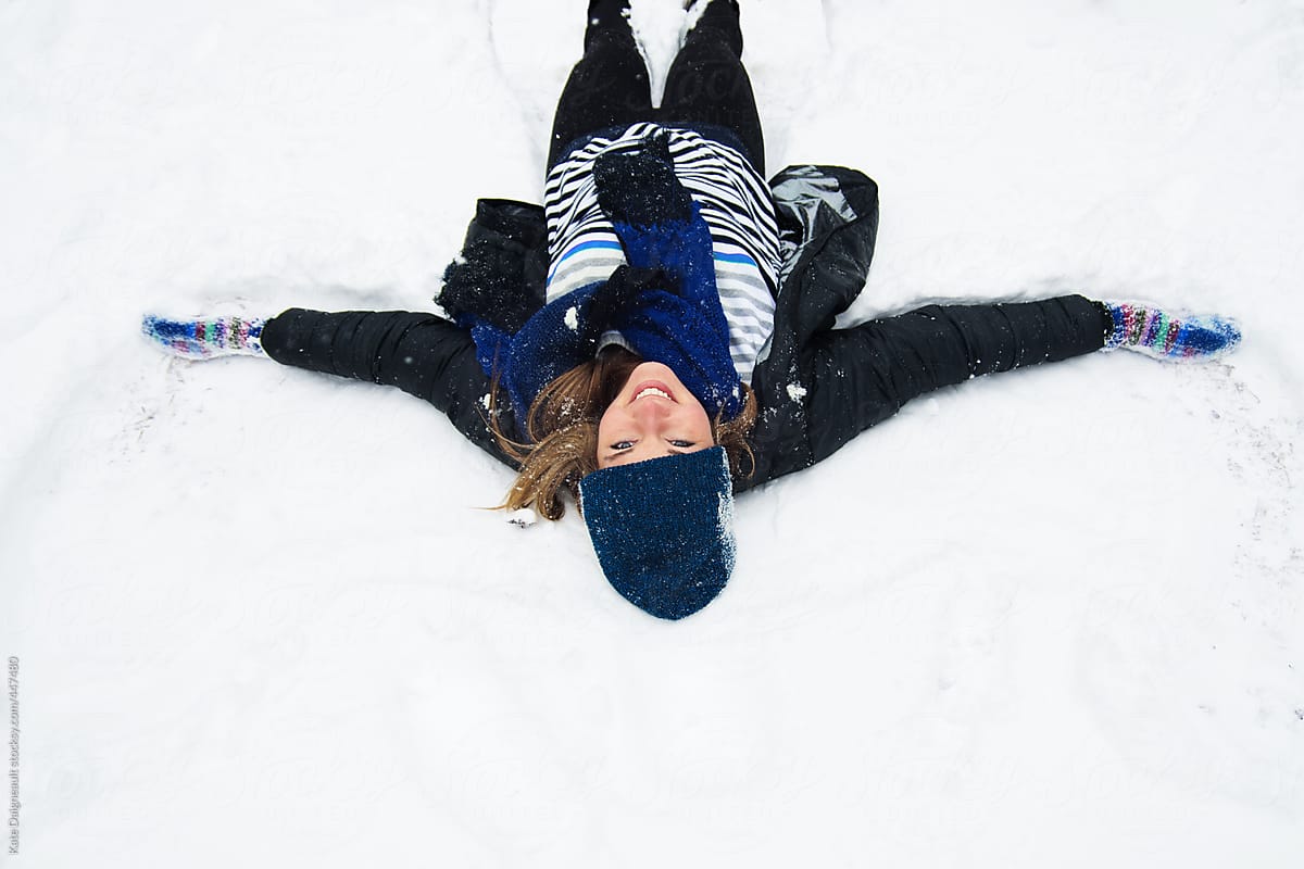 Young woman happily making a snow angel