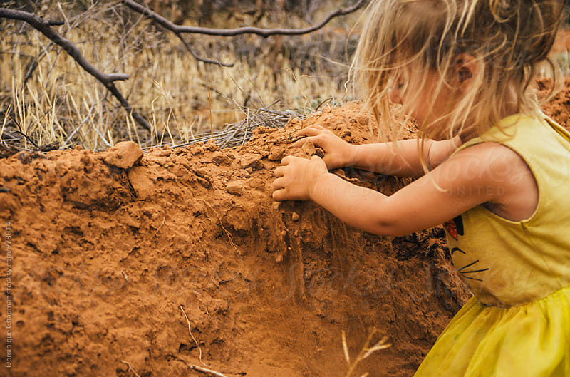 Little girl playing with red dirt
