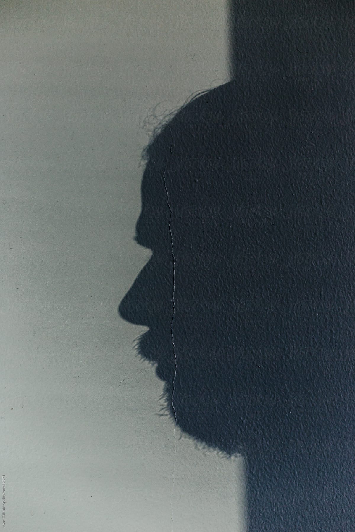 Man's face exiting from the shadow on the wall