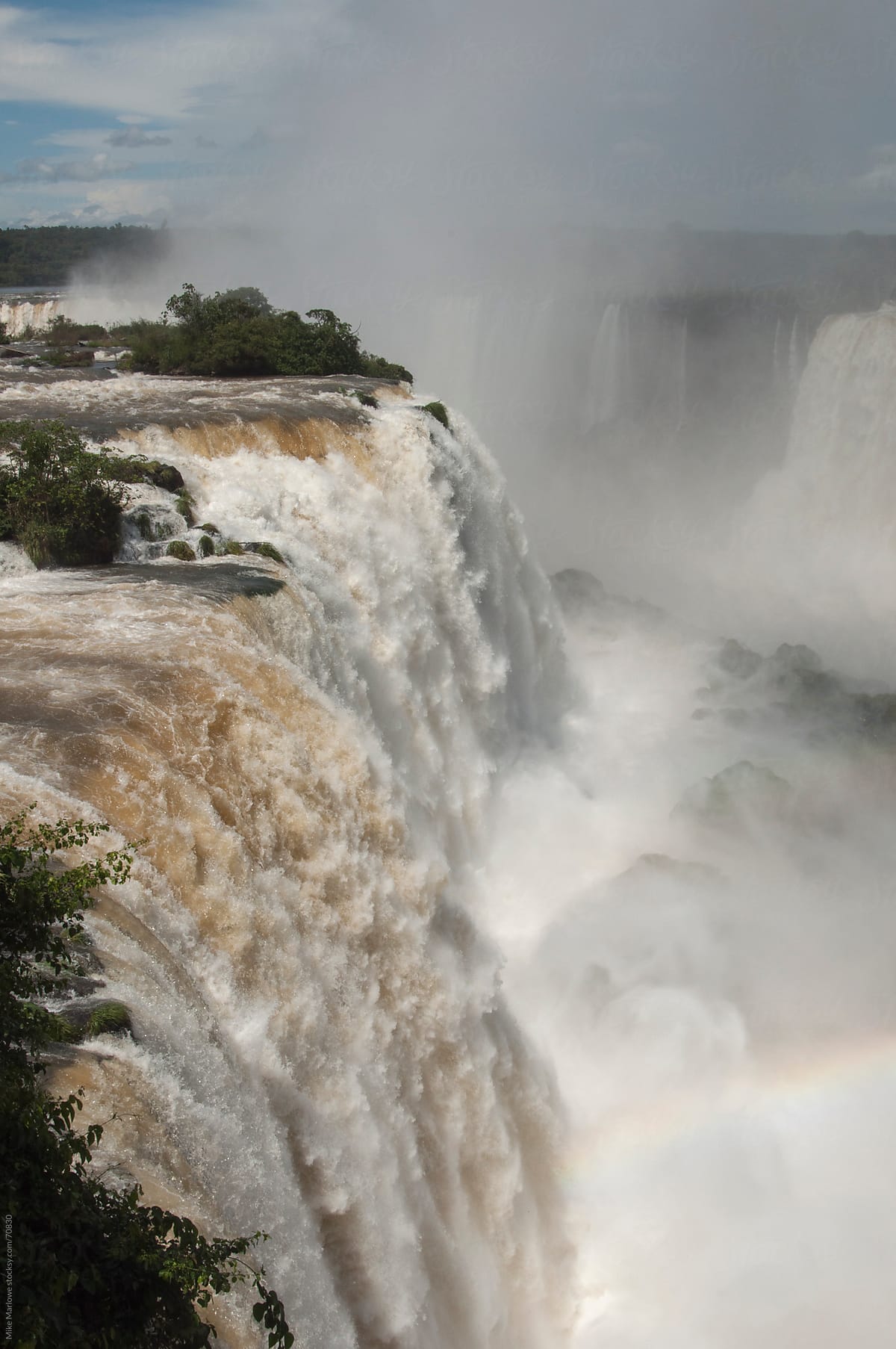 Vertical shot of Iguazu falls with fine mist rising in to the ai