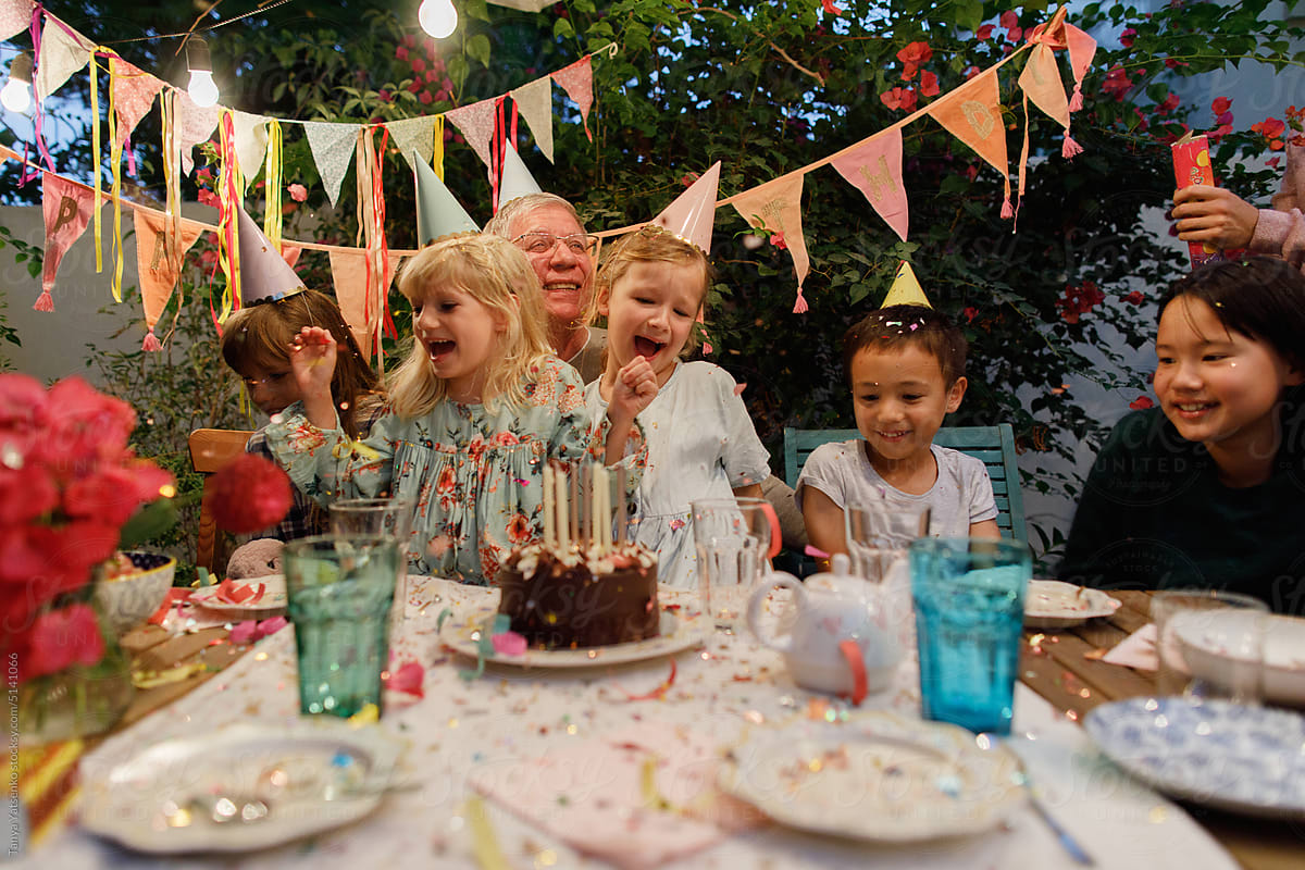 Grandfather and grandchildren with a birthday cake in a garden