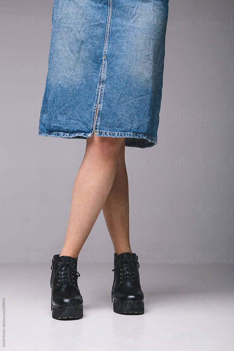 Close-up of woman\'s legs in stylish black leather shoes and denim skirt