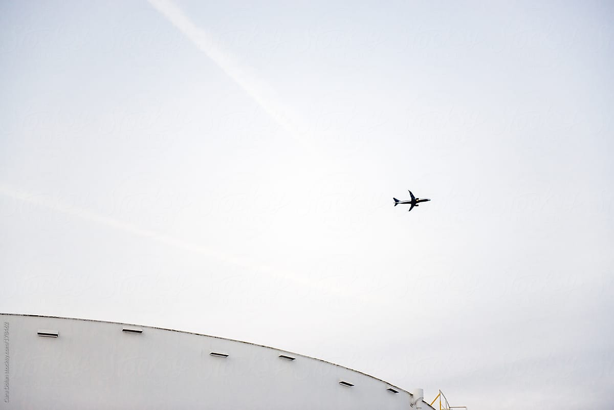 Industrial fuel storage tank with airplane taking off in the distance