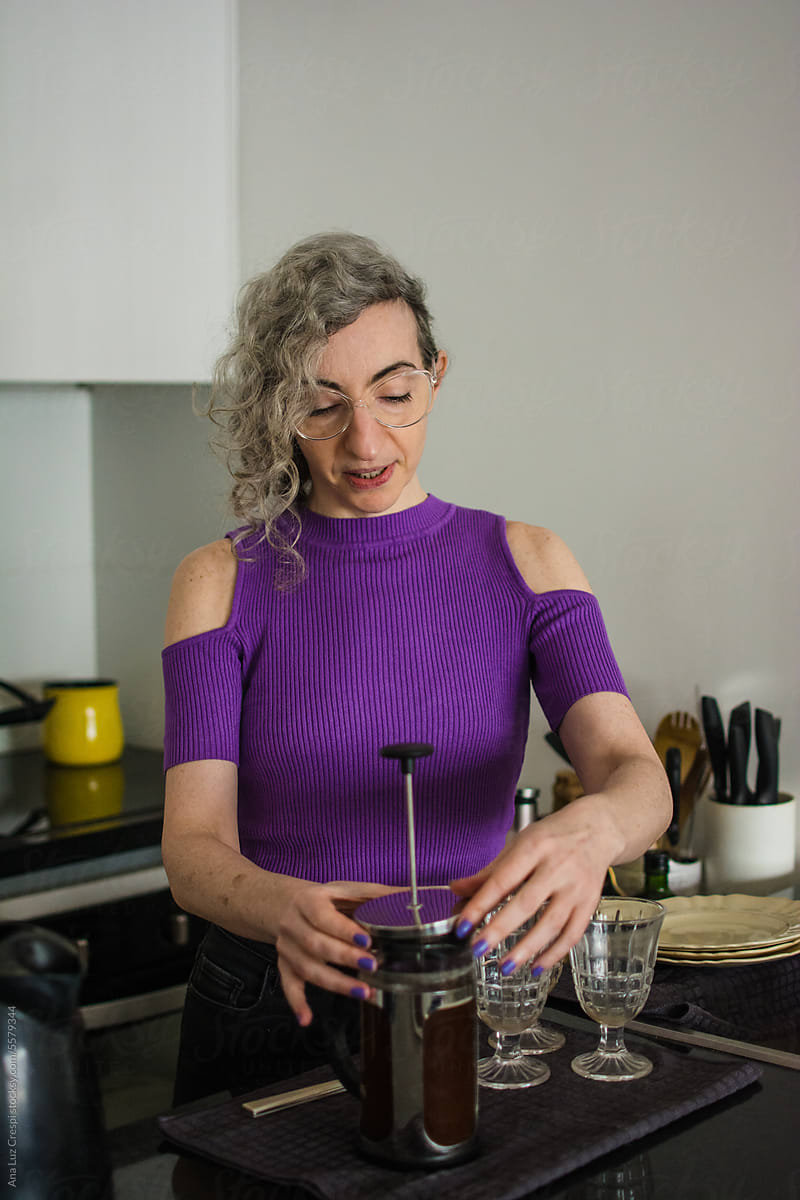 Woman with grey hair making coffee with french press