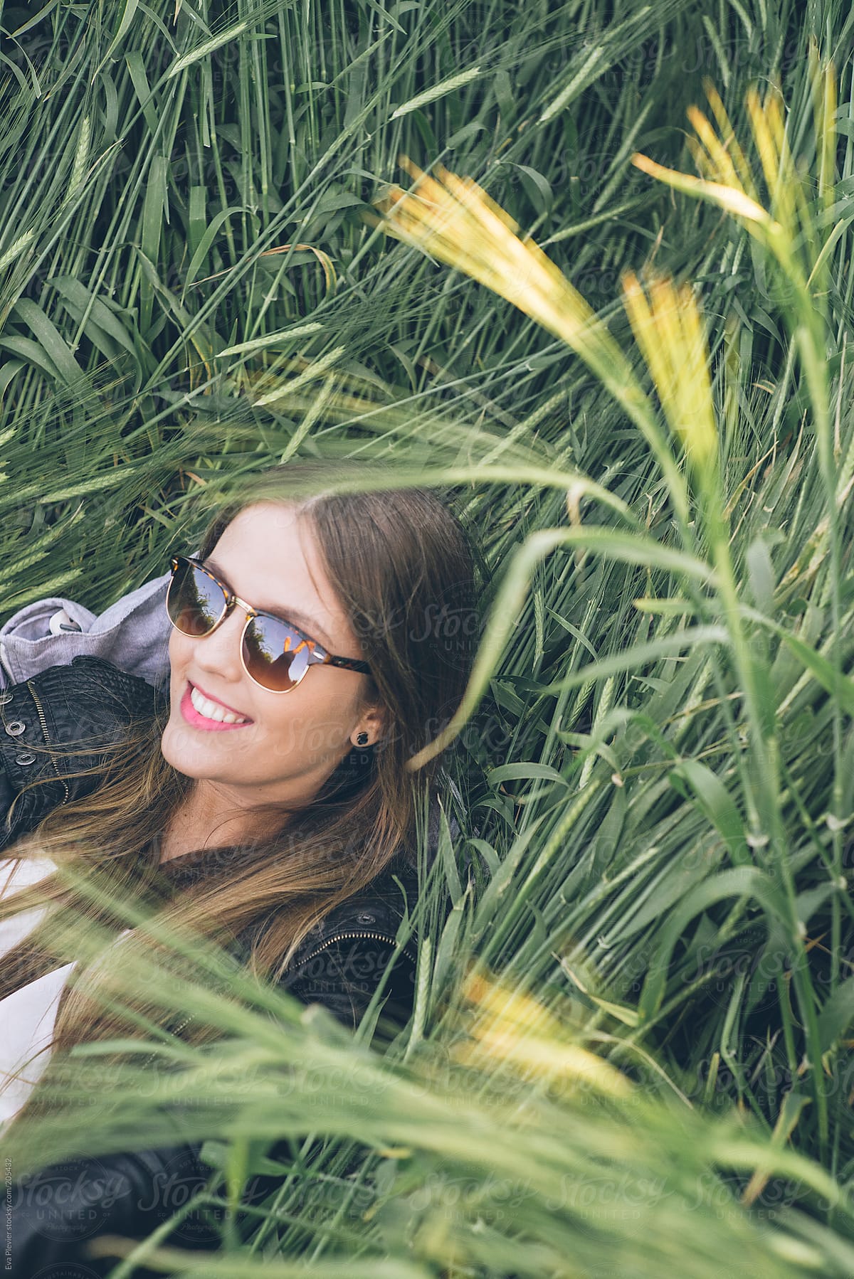 Happy Young Woman Lying Down In The Grass By Stocksy Contributor