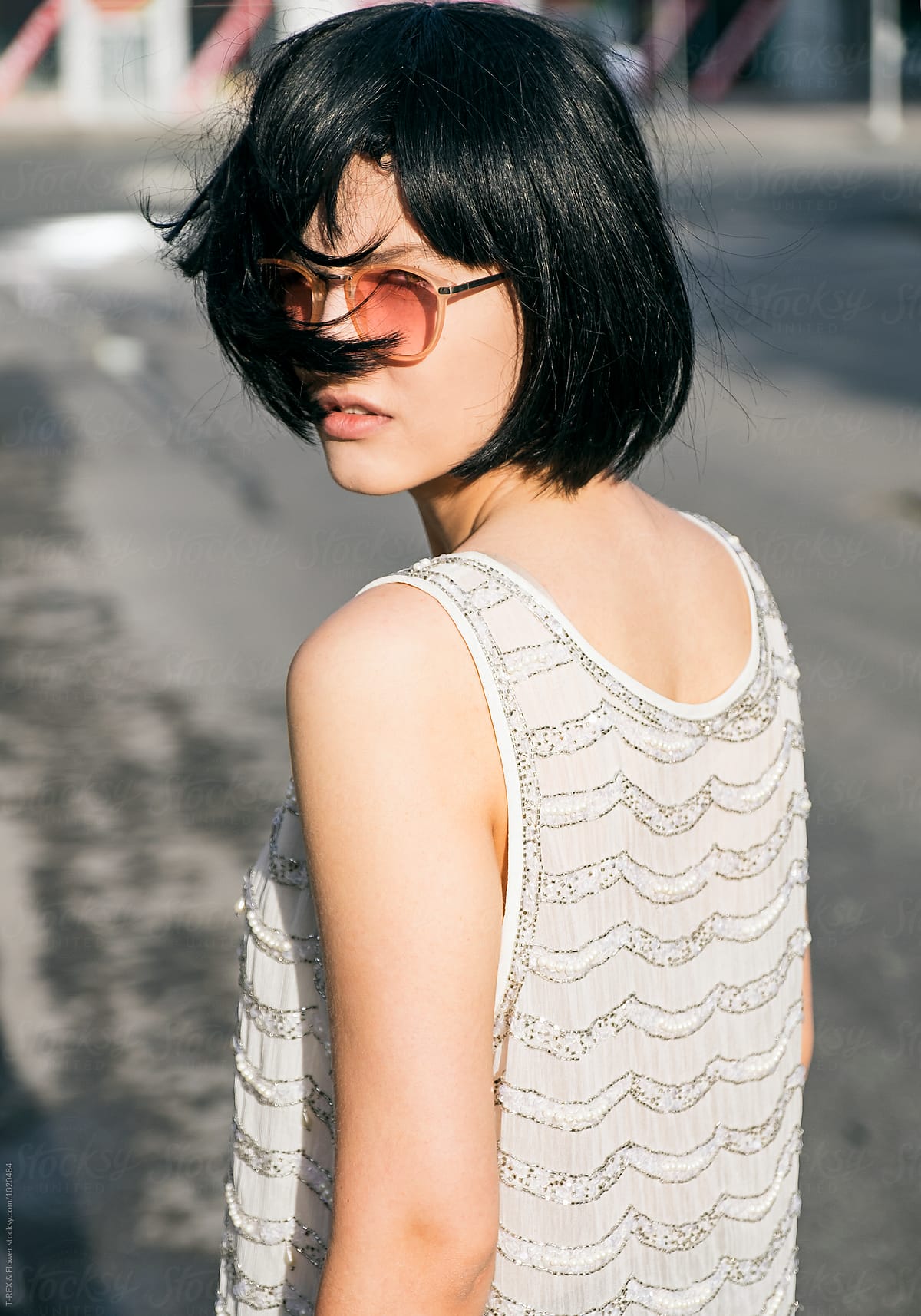 Attractive Black Haired Girl In Sunglasses Looking At Camera Overshoulder By Stocksy