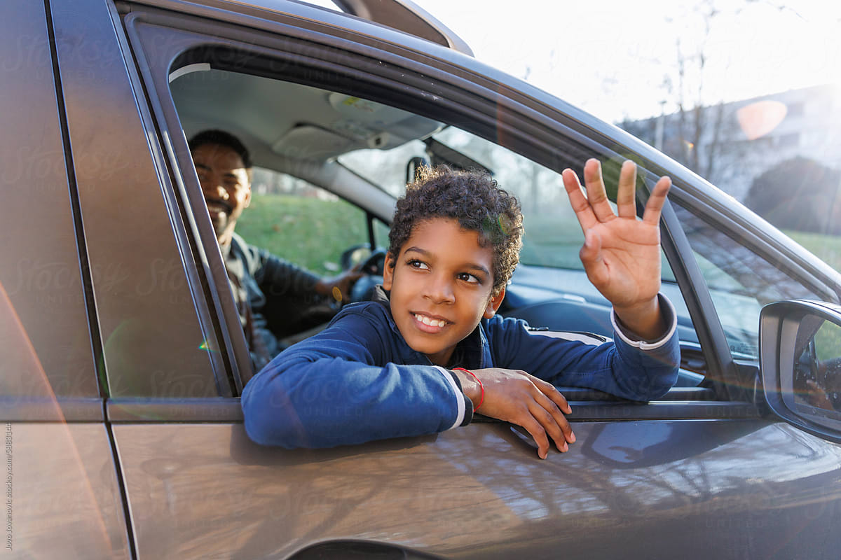 Happy boy waving through car window
