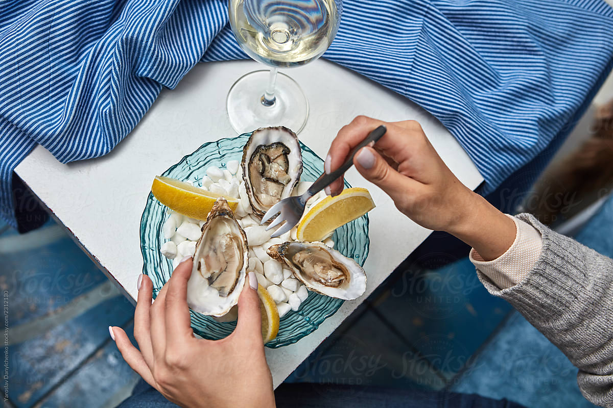 The girl's hands hold a fork and open fresh oyster