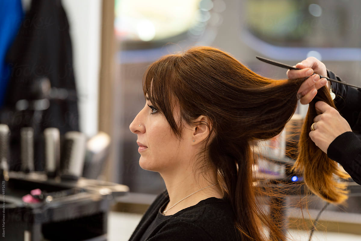 Stylist making hairdo to client in salon