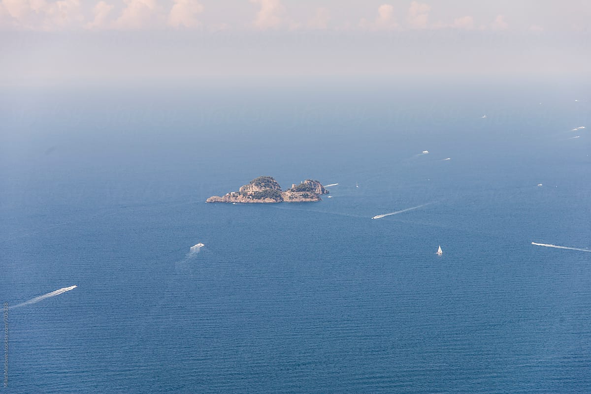 Distant shot of an island with boats crossing the sea around it