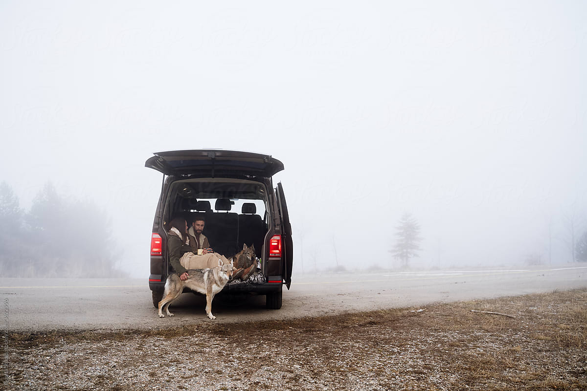 Young couple in a camper van in nature during winter in a foggy day