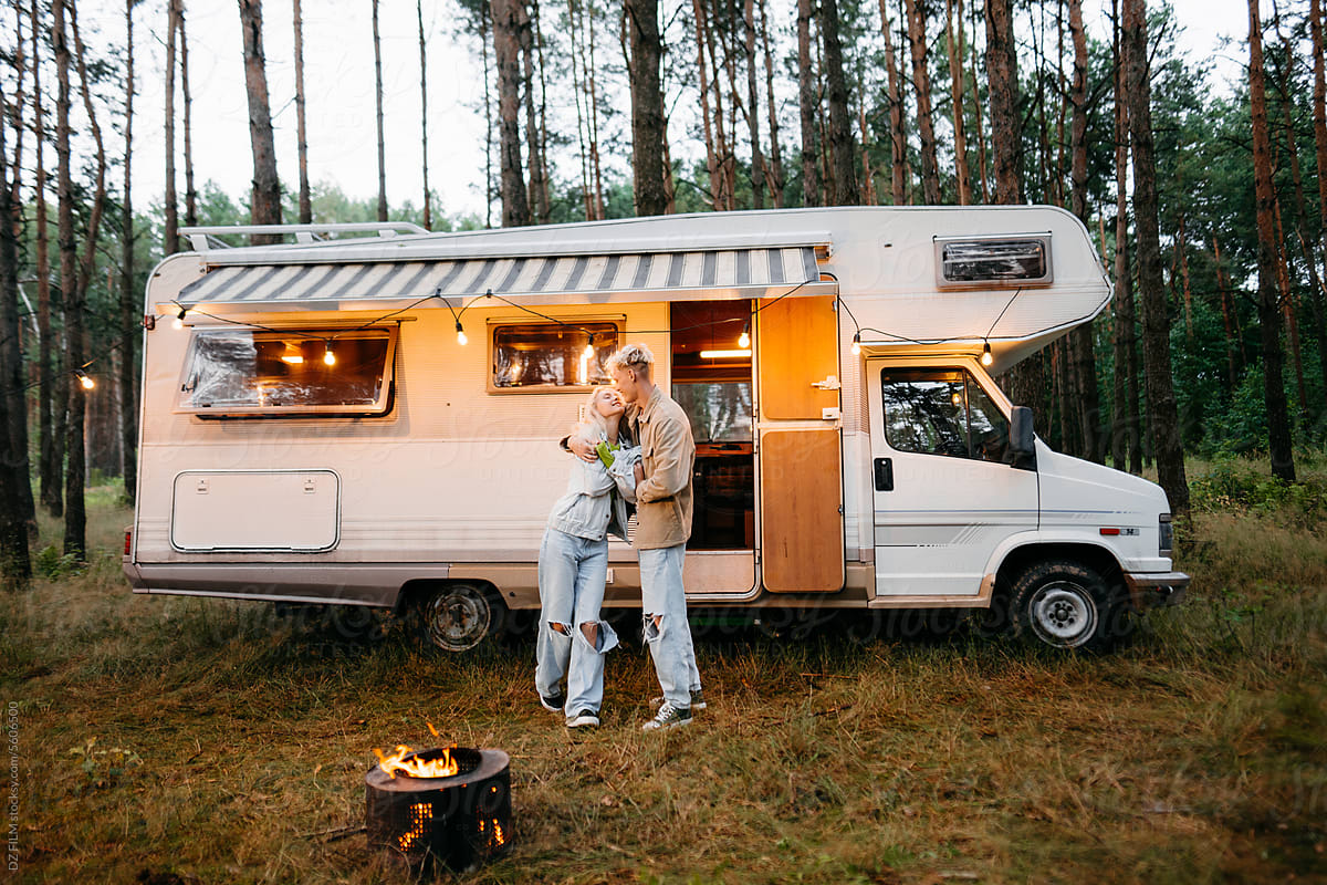 A man and a woman are standing near the RV