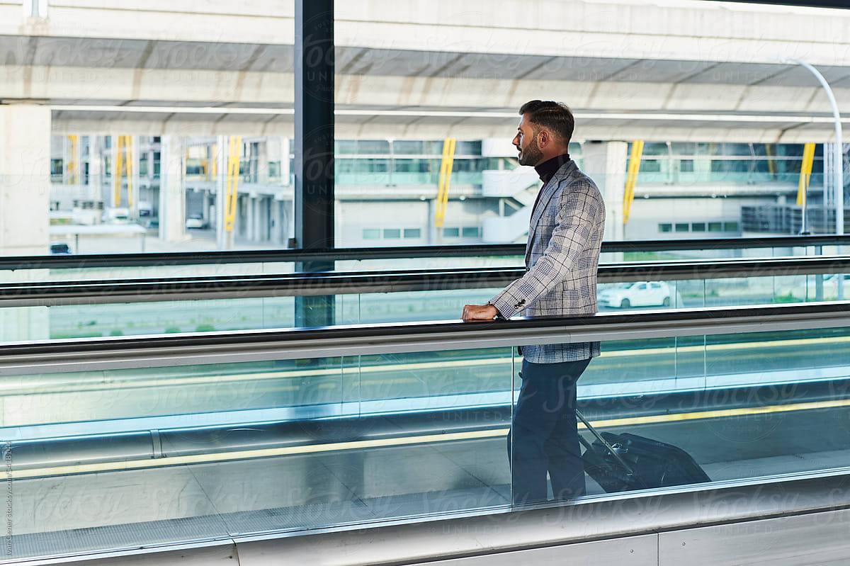 Man standing with luggage on an airport moving walkway