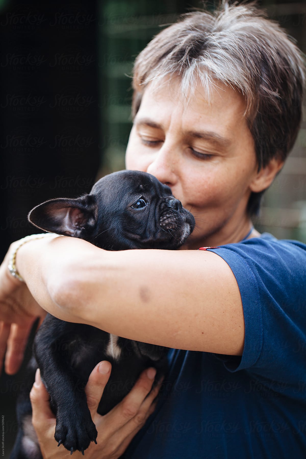 Woman holding in her arms and cuddling a French Bulldog puppy dog