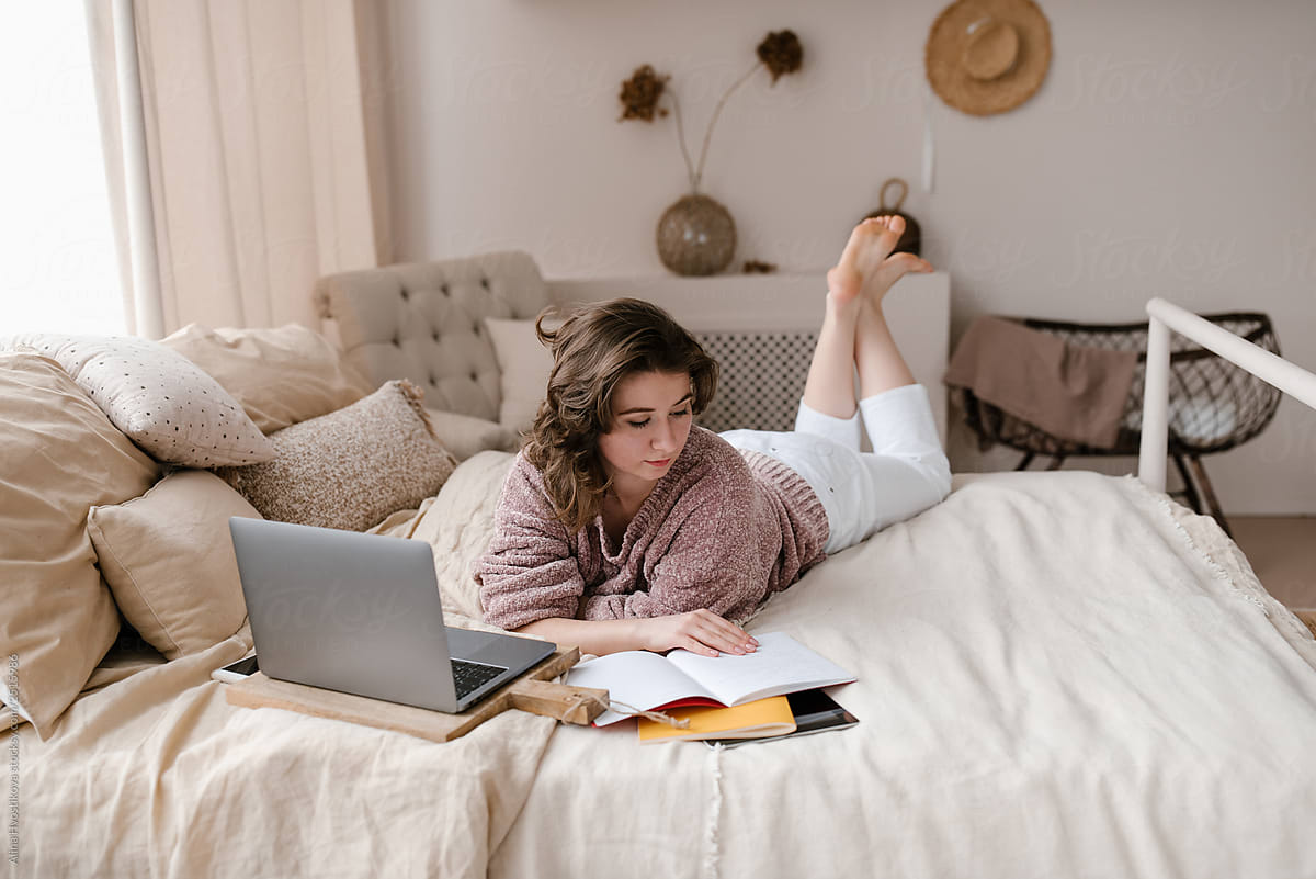Barefoot freelancer reading notes on bed