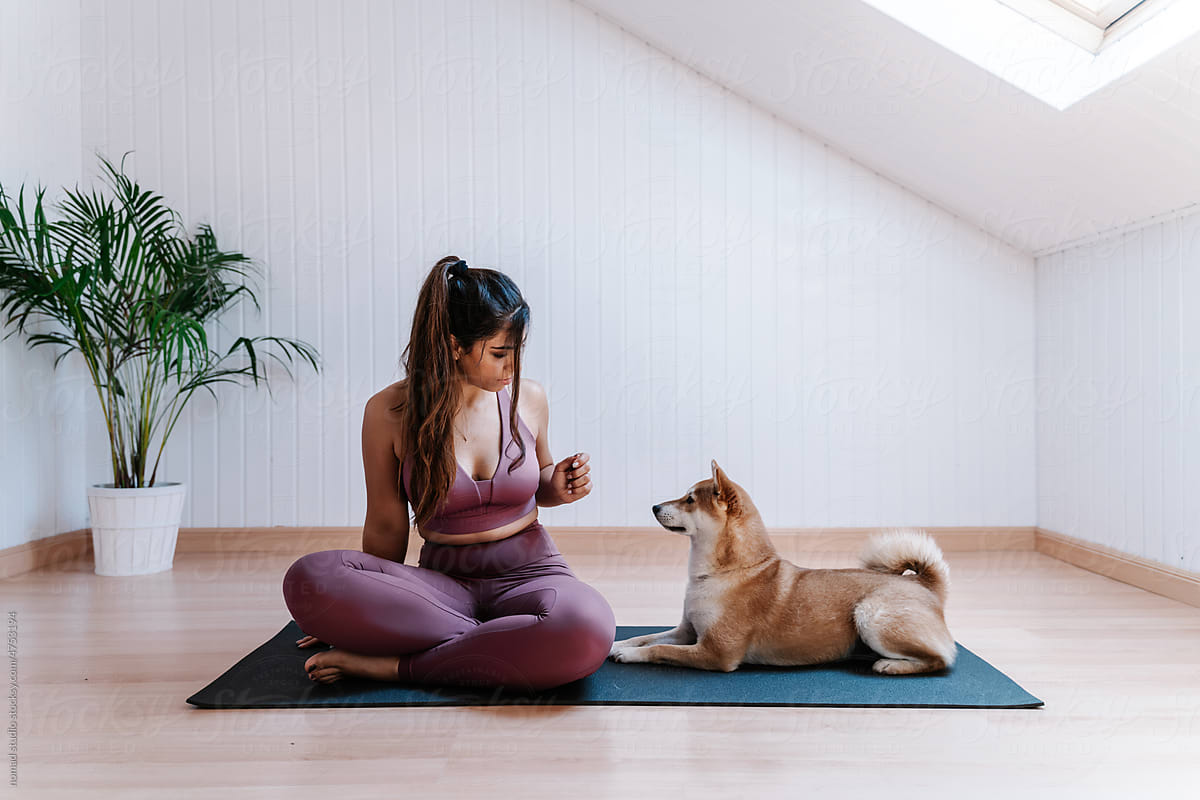 Sporty woman with dog resting on yoga mat