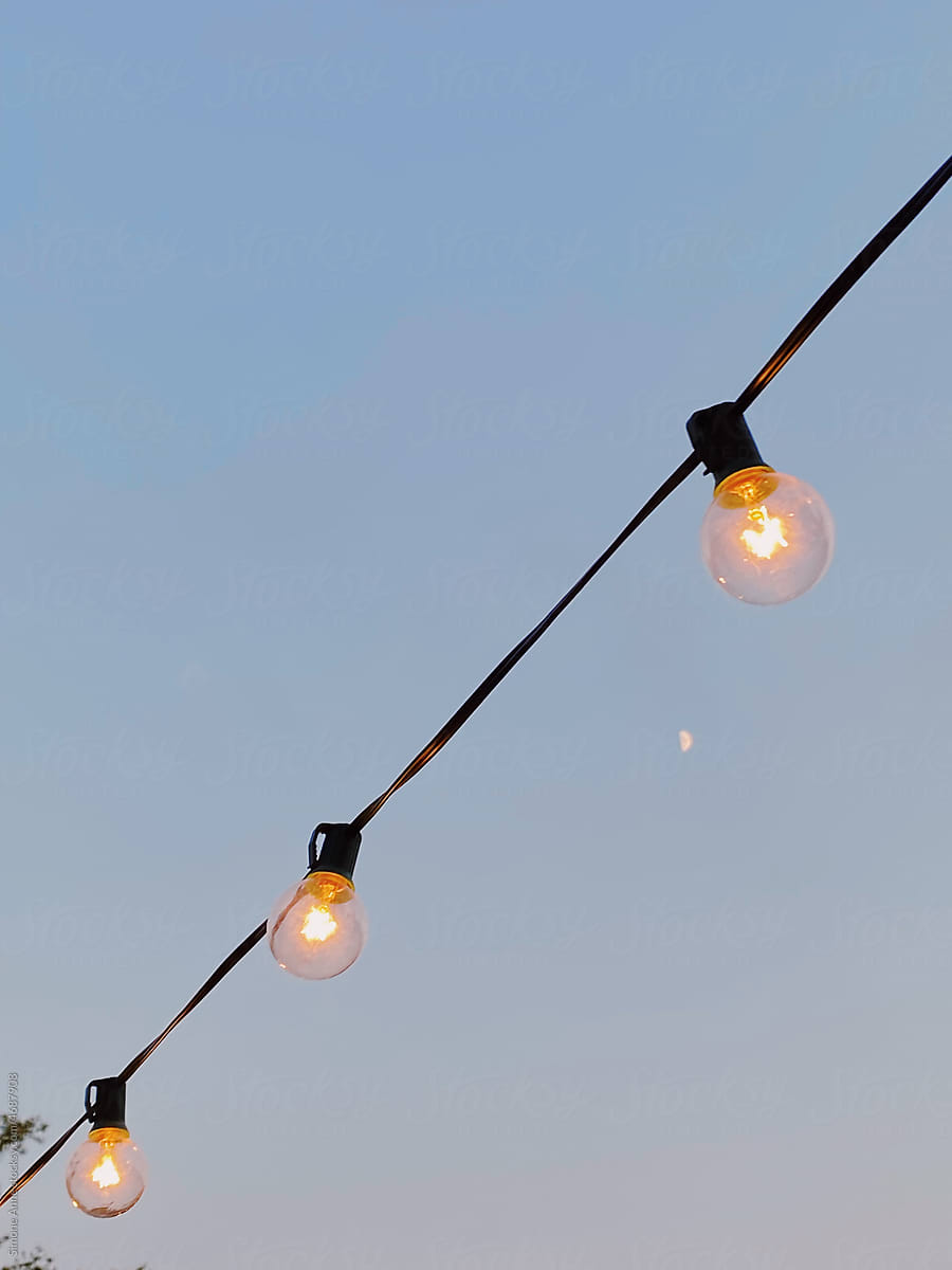 Twinkle lights hang in the sky with a tiny moon behind.