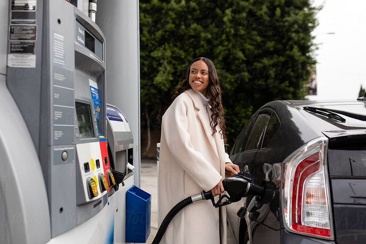Fashionable Woman Smiles While She Fills Up Her Car With Gas
