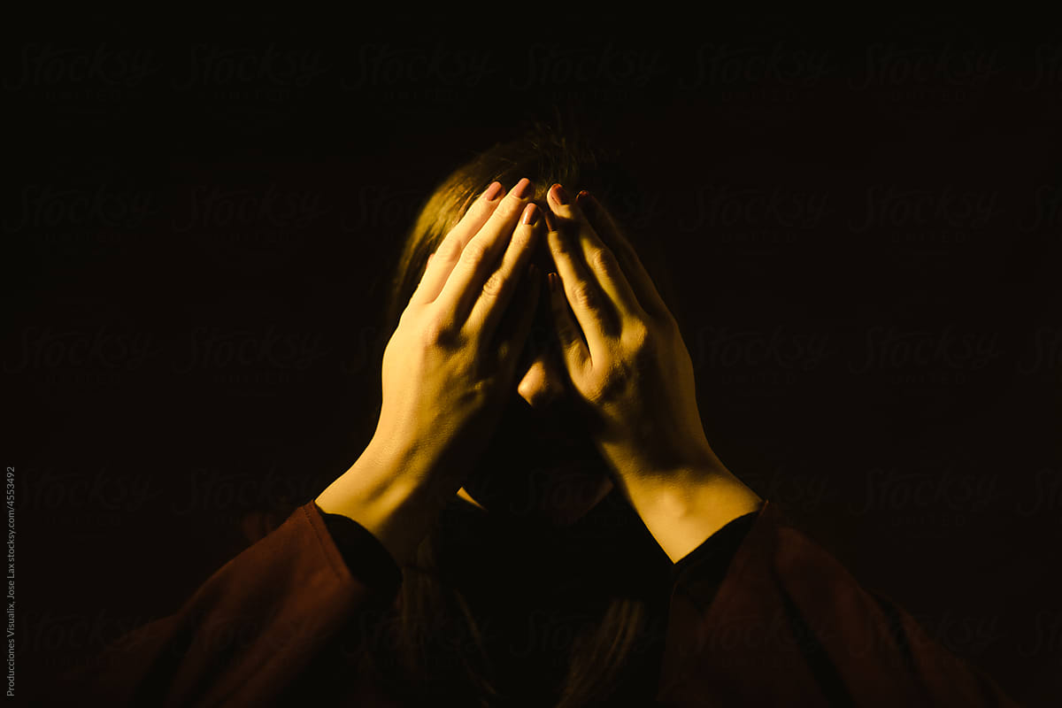Woman covering her face with her hands with a sense of fear.