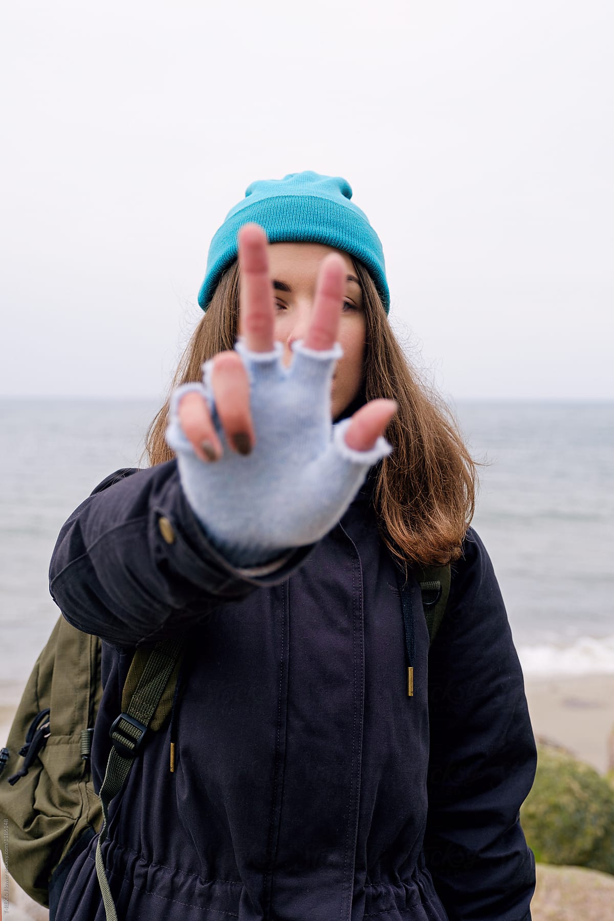 Girl shows two fingers sign at beach.