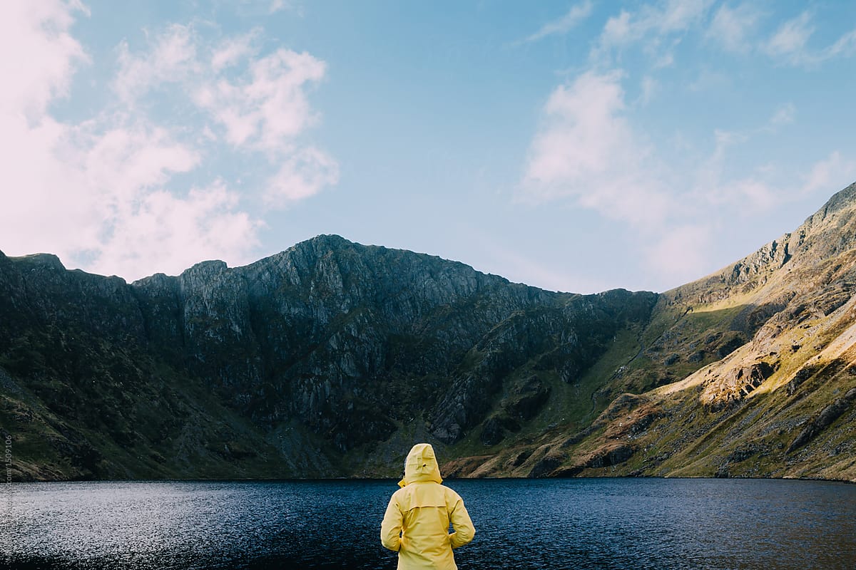 A Girl in a Bright Yellow Hoodie with a Smile on Her Face Sits on a Lake in  the Mountains and Looks at the Smartphone Stock Photo - Image of lake,  landscape