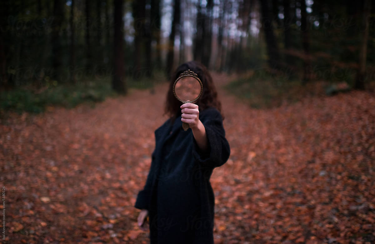Anonymous woman holding mirror in forest