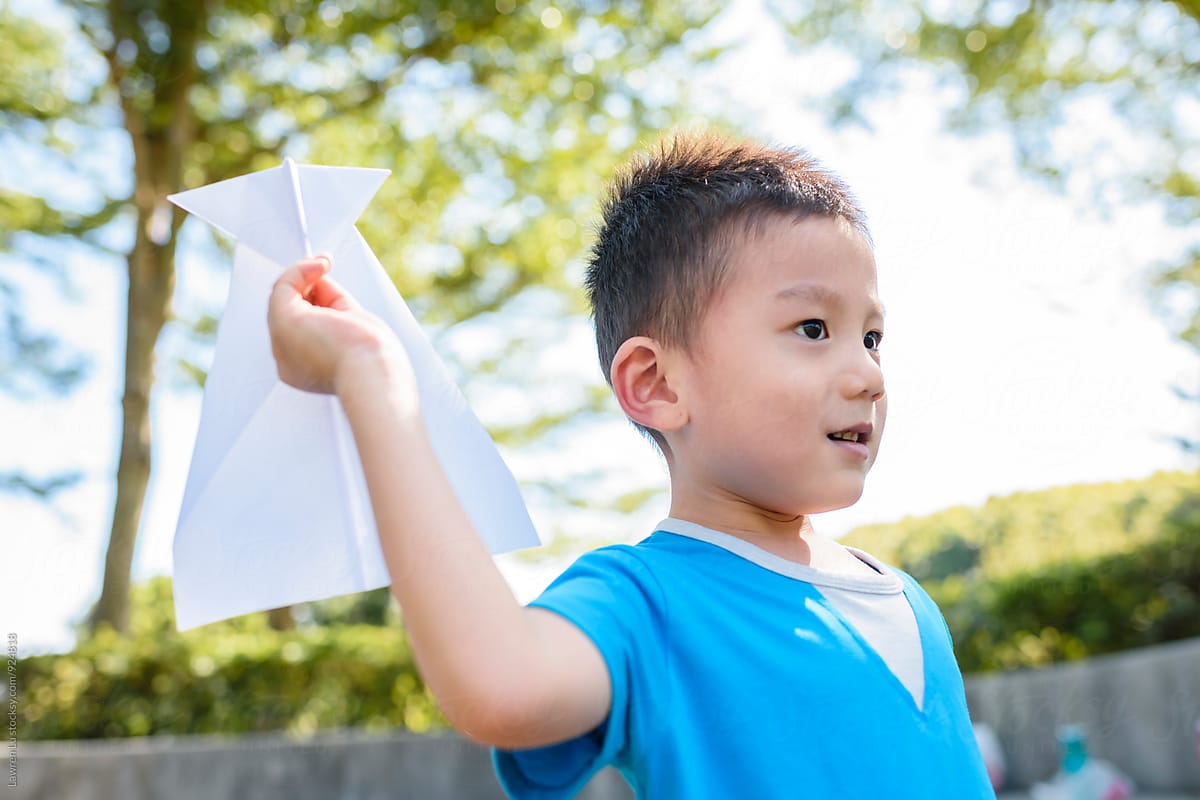 Kid playing paper airplane in sunlight